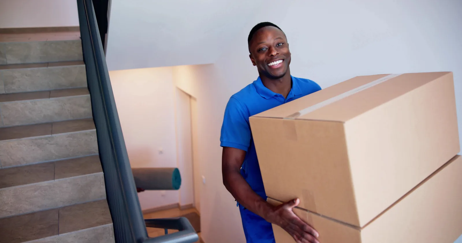 A Melbourne Deceased Estate Clearance team member carrying packed boxes down a staircase during a clearance