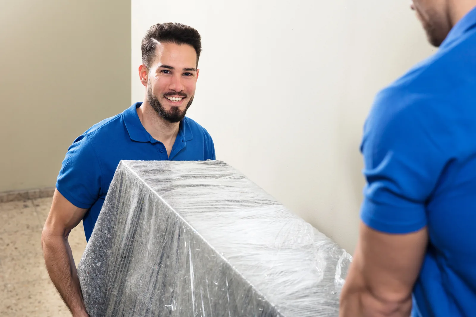Two Melbourne Deceased Estate Clearance team members carefully carrying a wrapped piece of furniture from a property